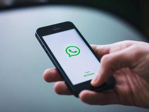 A mobile phone displays the loading screen of messaging service, WhatsApp
