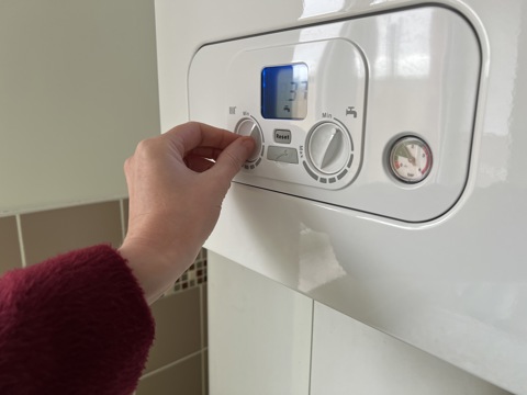 A hand turning on a heating boiler