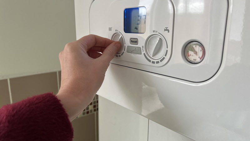 A hand turning on a heating boiler