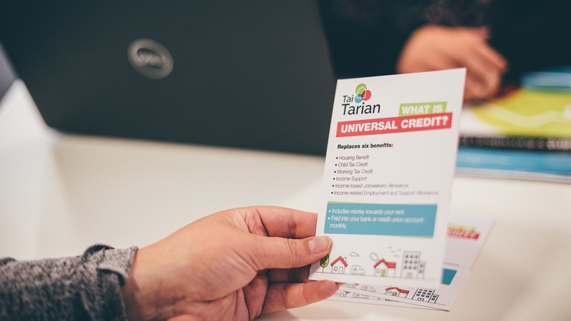 Tenant holding a Tai Tarian Universal Credit information leaflet